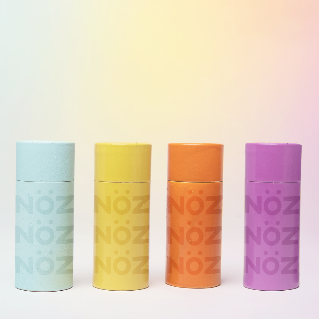 Nöz sunscreen earth friendly containers in blue, yellow, orange, and purple.