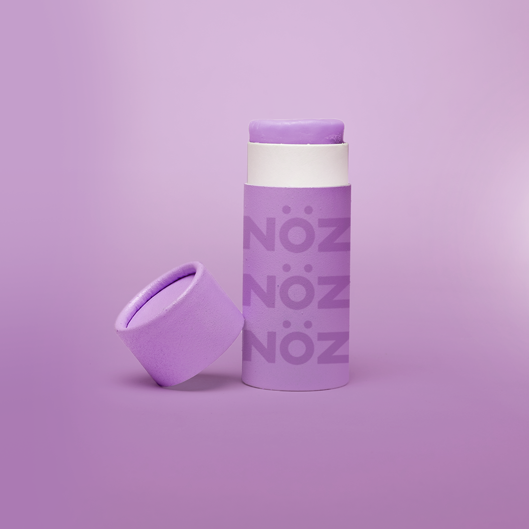 Close up of Nöz sunscreen in the color purple in earth friendly container with the lid off