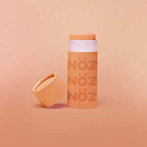 Close up of Nöz sunscreen in the color orange in earth friendly container with the lid off