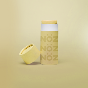 Close up of Nöz sunscreen in the color yellow in earth friendly container with the lid off