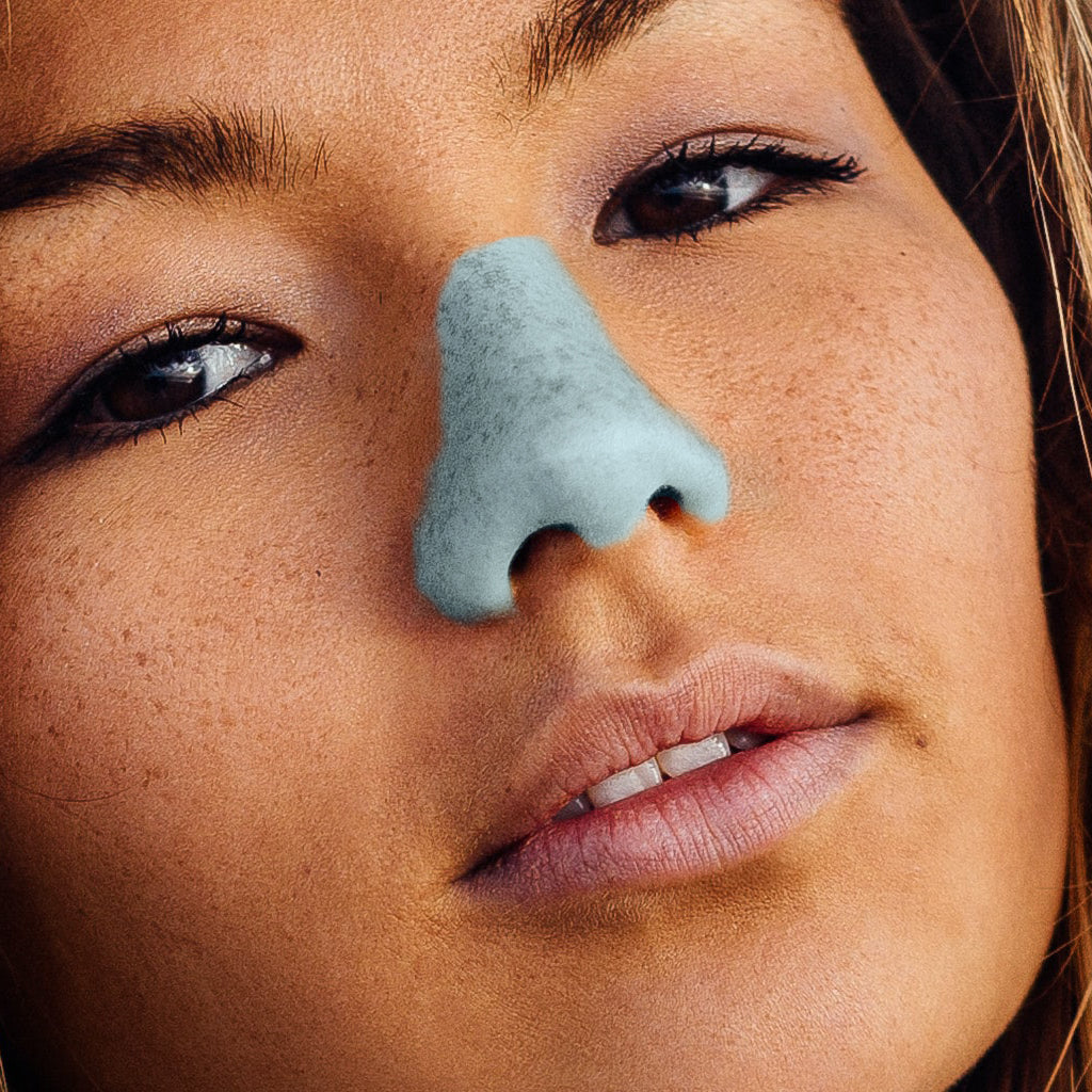 Close up front view of woman with blue Nöz sunscreen on her nose.